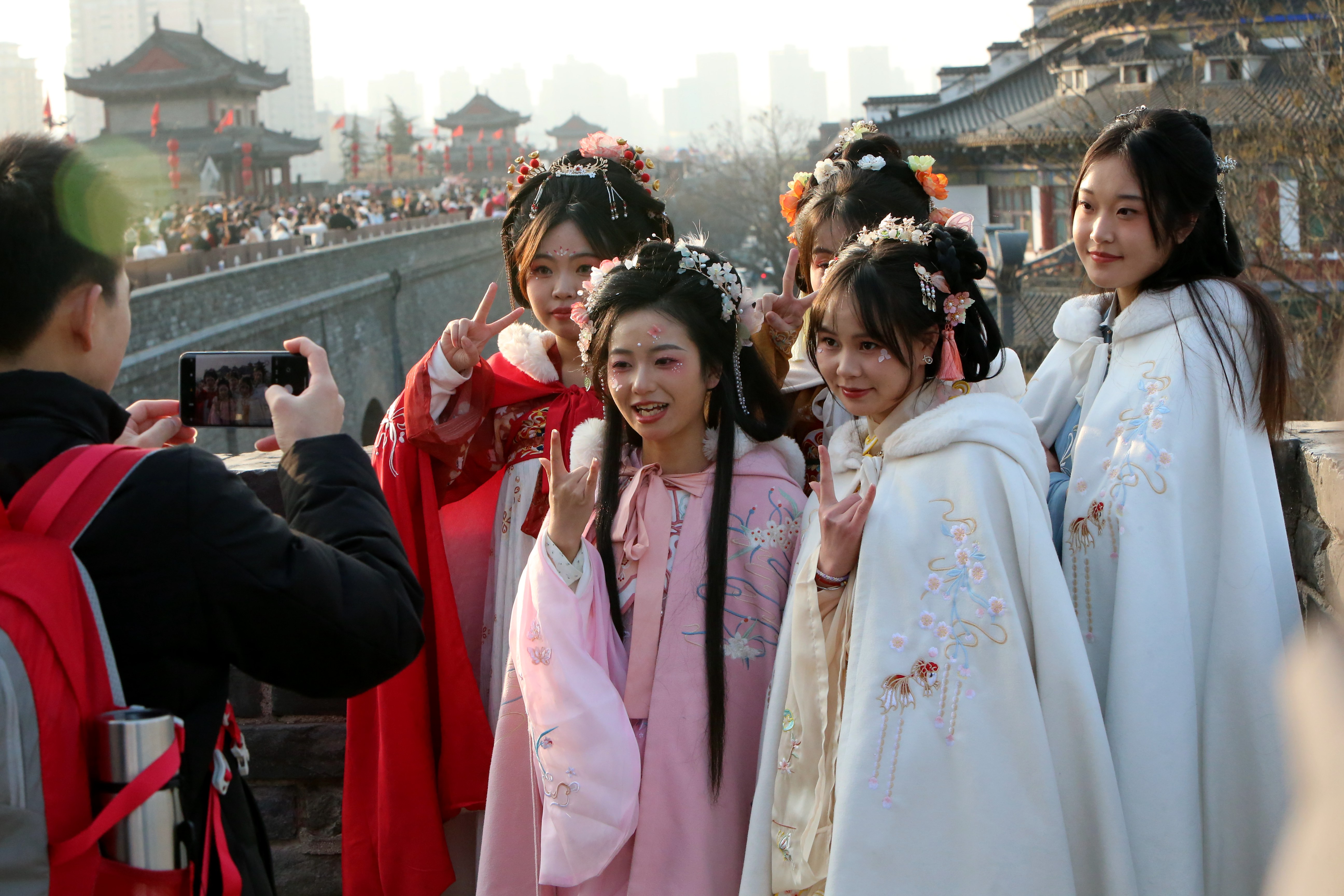 Tourists wearing hanfu, the traditional costume of the Han Chinese people, take photos on the ancient city wall of Xi'an in northwest China's Shaanxi Province on December 23, 2023. /IC