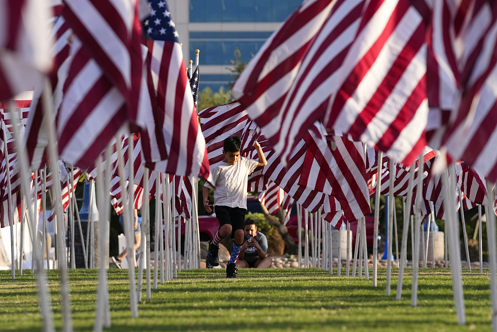 2023 年 9 月 11 日，美国亚利桑那州坦佩，一名游客沿着展示的一些美国国旗之间的小路奔跑，这里形成了坦佩治疗场，以纪念 9 月 11 日恐怖袭击的近 3,000 名受害者。/CFP
