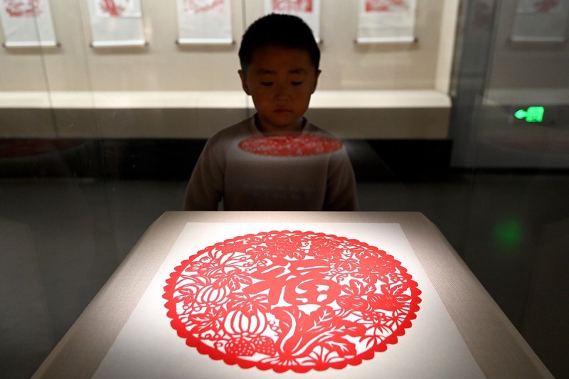 A photo shows a boy examining a paper-cutting work at Handan Museum in Handan, Hebei Province, January 1, 2024. /IC