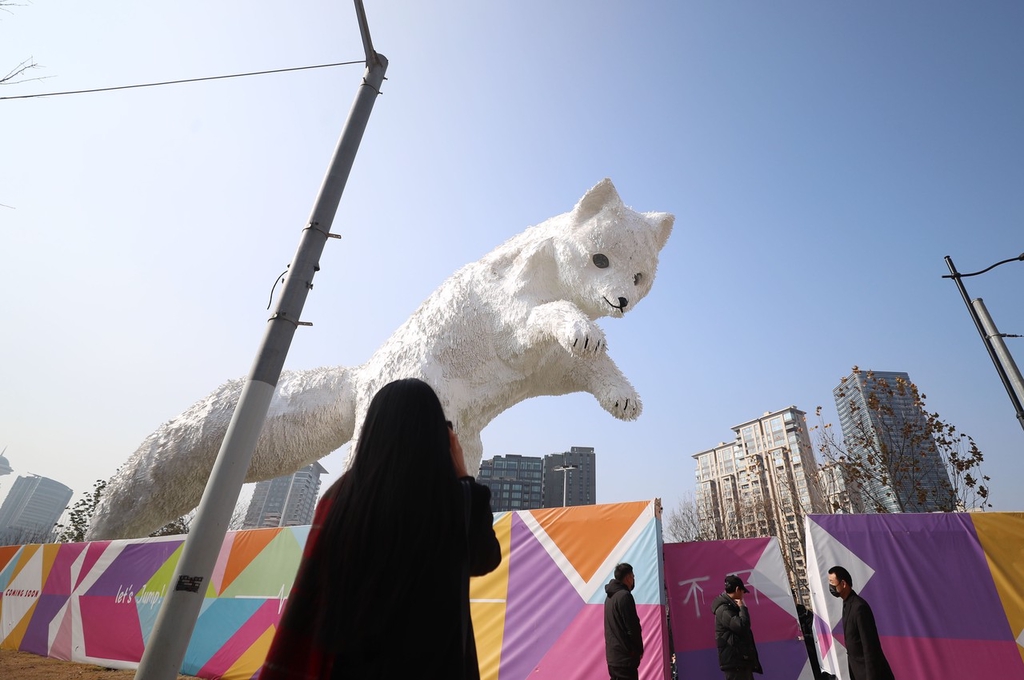A photo shows pedestrians stopping to look at an Arctic fox installation on a street corner in Shanghai on January 2, 2024. /IC