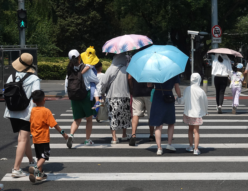 Tourists walk down the street during a heat wave in Beijing, July 19, 2023. /CFP