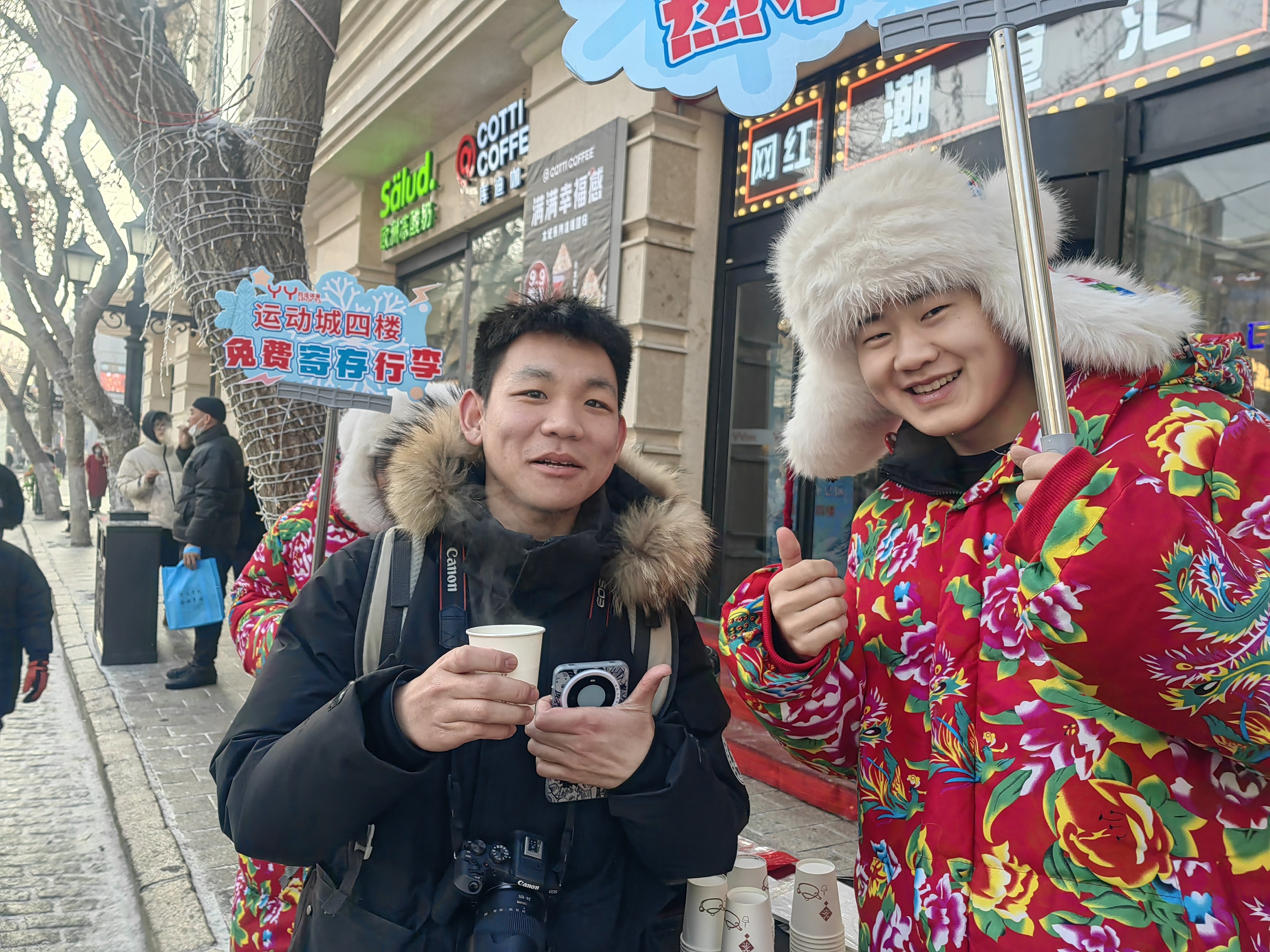 A staff member of a shopping mall (R) provides free warm water for a tourist on the Central Street of Daoli District, Harbin, January 3, 2024. /CFP