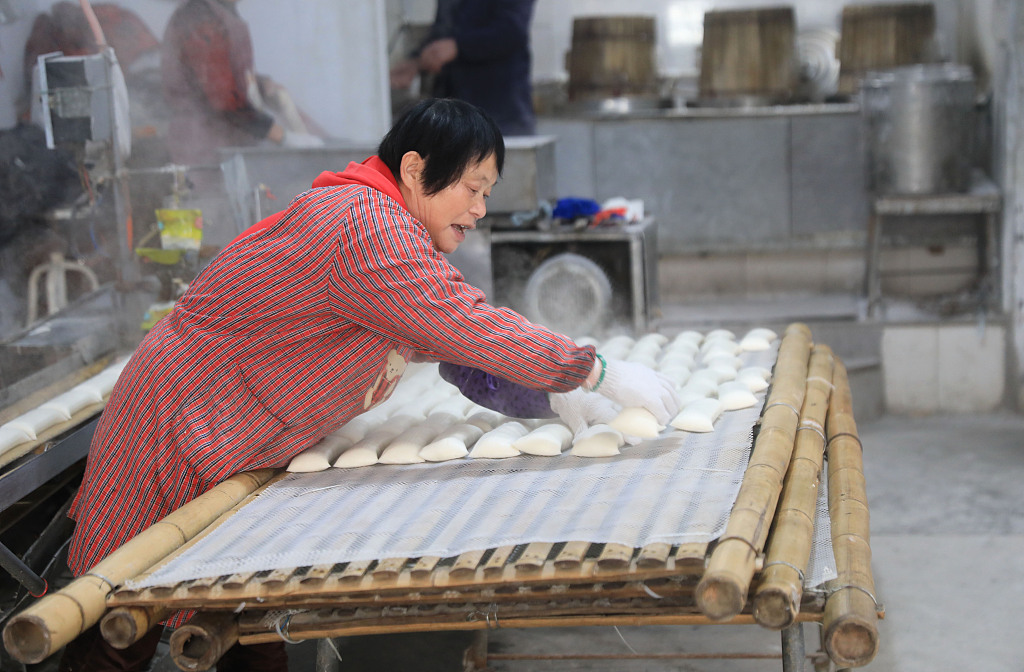 Photo taken on January 3, 2024 shows a woman making rice cakes in a small workshop in Zhoushan, Zhejiang Province. /CFP