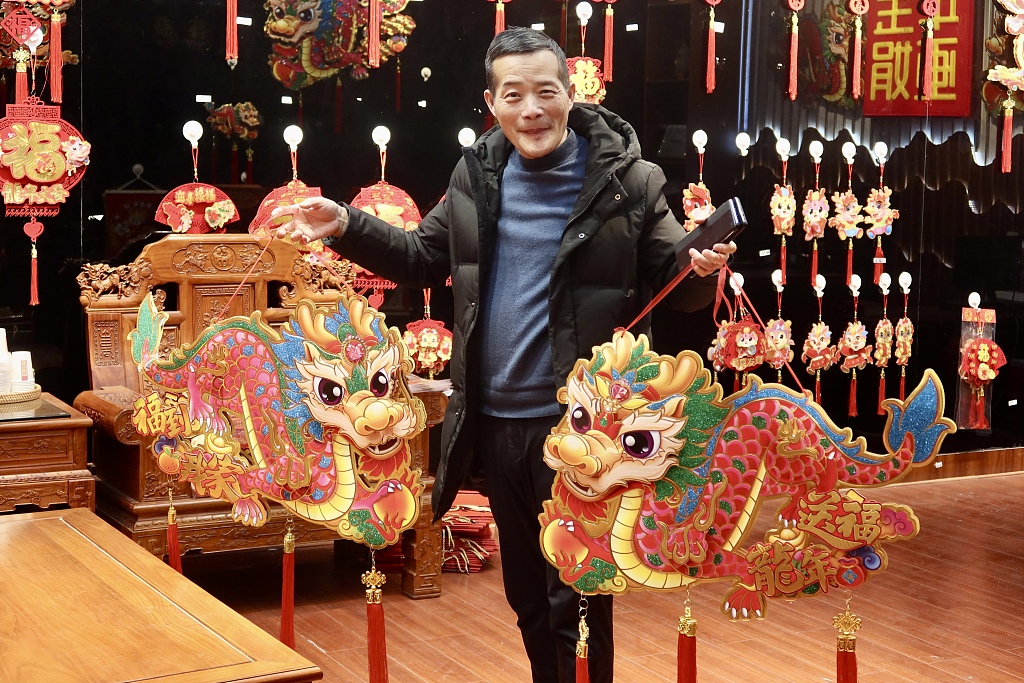 Photo taken on January 3, 2024 shows a consumer displaying a pair of loong ornaments he just purchased in Yiwu, Zhejiang Province. /CFP