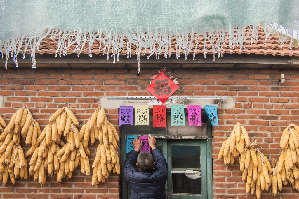 Photo taken on January 3, 2023 shows a craftsman hanging guomenjian on door lintels in Juxian County, Shandong Province. /CFP