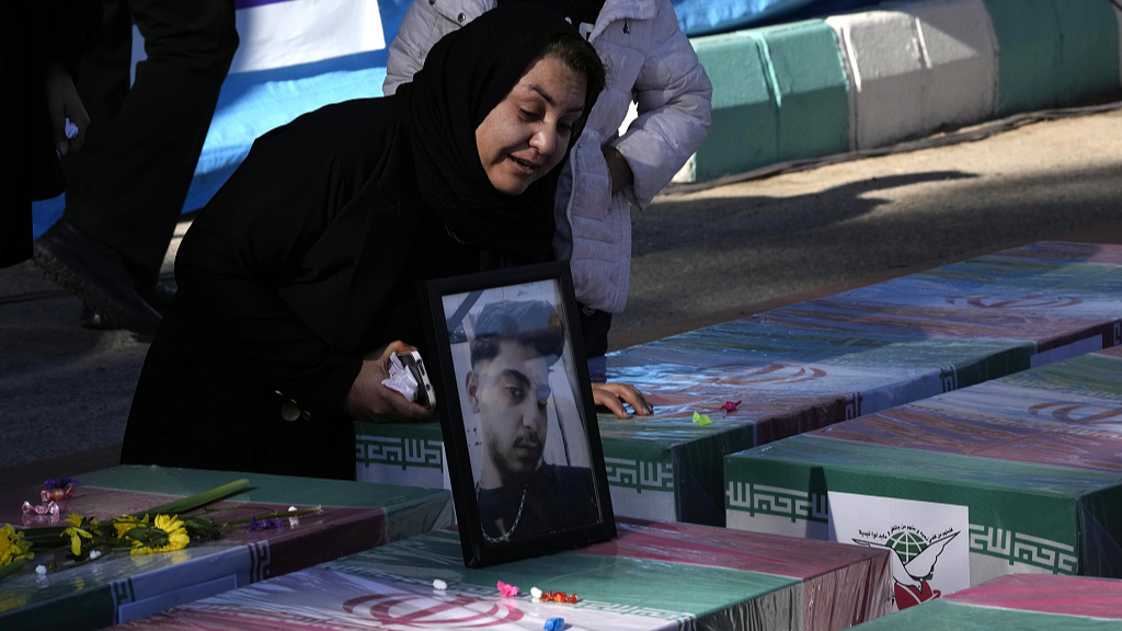 A woman mourns over the flag-draped coffin of her son who was killed in Wednesday's bomb explosion, during a funeral ceremony in Kerman, Iran, January 5, 2024. /CFP