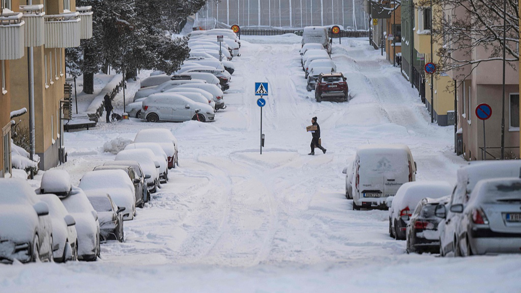 A man crosses a street after snowfall in Sundbyberg, near Stockholm in Sweden, January 4, 2024. /CFP