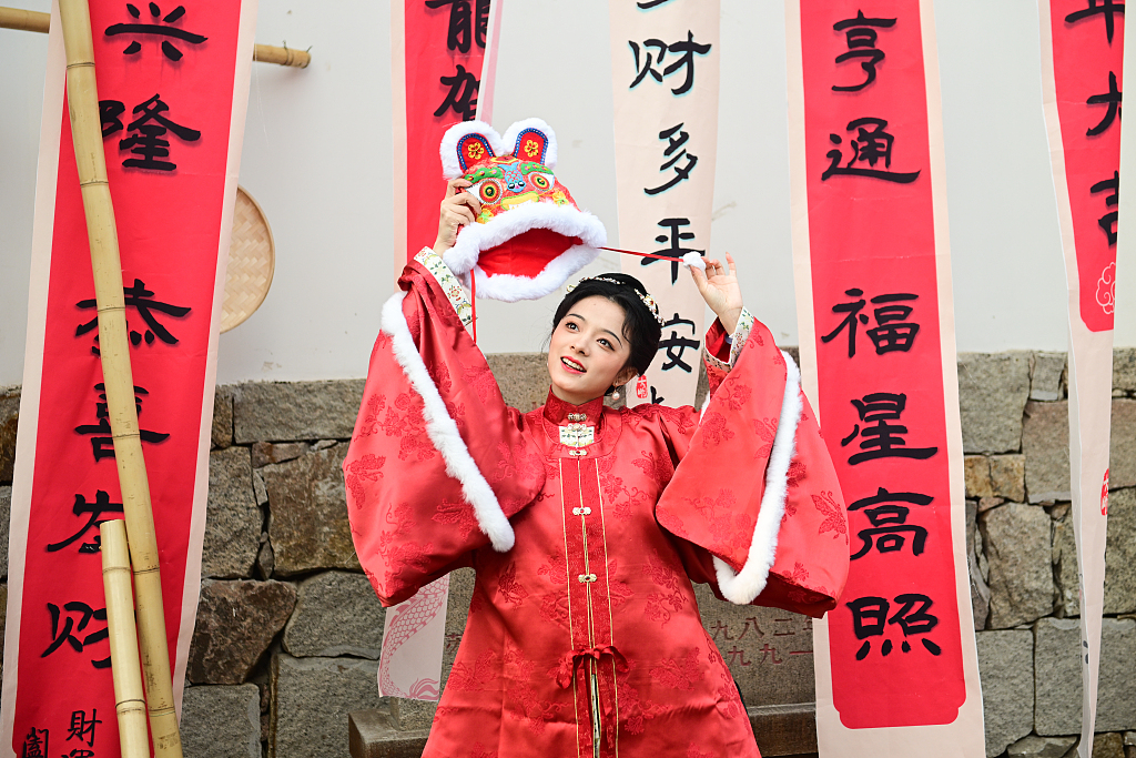 A tourist wearing a traditional costume poses for a photo in the Taohuawu street block in Suzhou, east China's Jiangsu Province, on January 1, 2024. /CFP