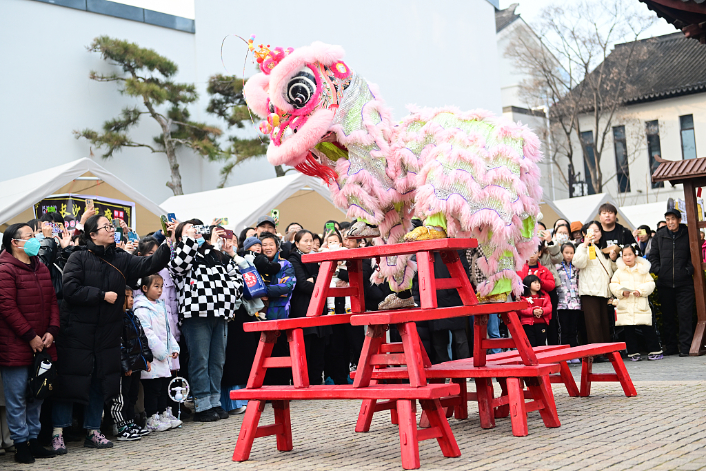 People watch a lion dance performance in the Taohuawu street block in Suzhou, east China's Jiangsu Province, on January 1, 2024. /CFP