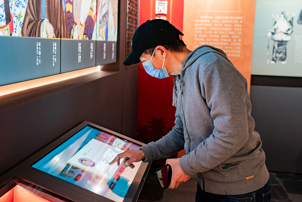 2024年1月5日，一位参观者在北京湖广会馆博物馆聆听利用数字技术再现的著名戏曲艺术家的表演。/CFP