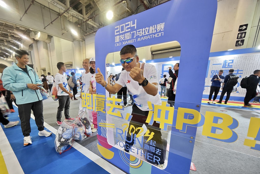 A visitor poses with the logo of the 2024 Xiamen Marathon during the fifth China Marathon Expo in Xiamen, China, January 6, 2024. /CFP