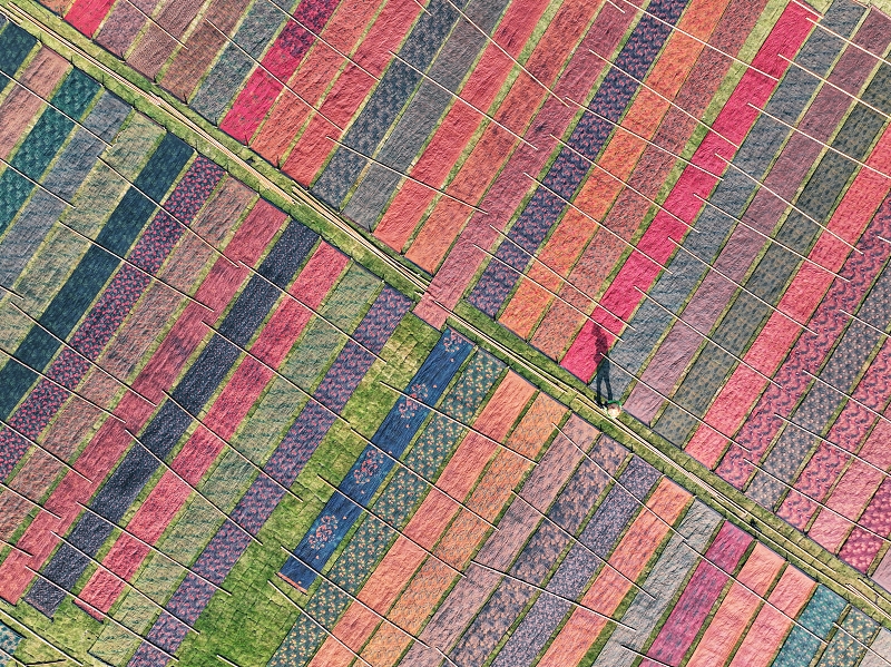 An aerial photo shows a worker airing colorful fabrics on a farm in Foshan City, Guangdong Province, January 5, 2024. /CFP