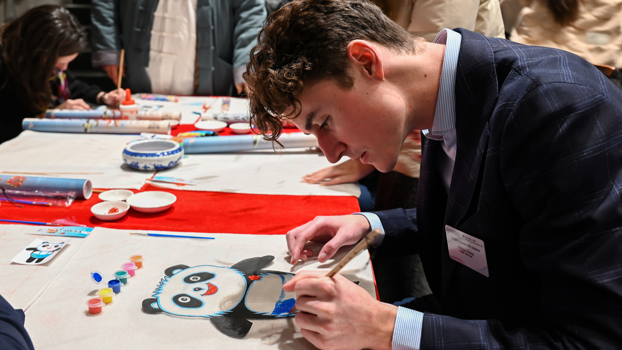 A young man from the U.S. draws a panda during a China-U.S. youth exchange event in Chengdu, southwest China's Sichuan Province, January 4, 2024. /CFP