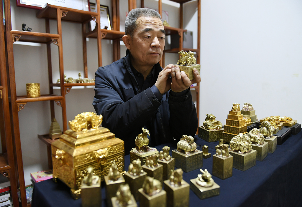 A photo taken on December 17, 2023 shows Wang Zhirong holding an engraved copper seal in Yuncheng, Shanxi Province, China. /CFP