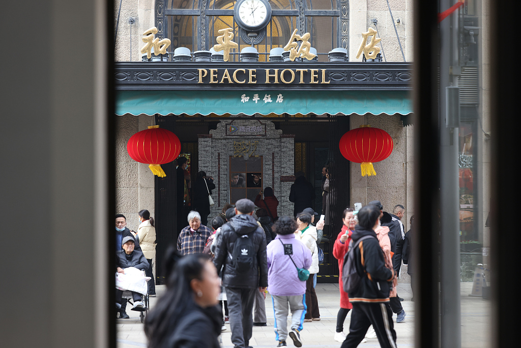 2024 年 1 月 9 日拍摄的照片显示，人们走在中国上海和平饭店前。  /CFP