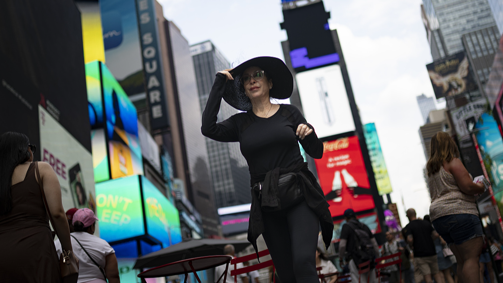Pedestrians cover themselves as they pass through Times Square while temperatures rise, New York, U.S., July 27, 2023. /CFP