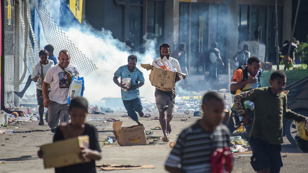 People run with merchandise as crowds leave shops with looted goods amid a state of unrest in Port Moresby, January 10, 2024. /CFP
