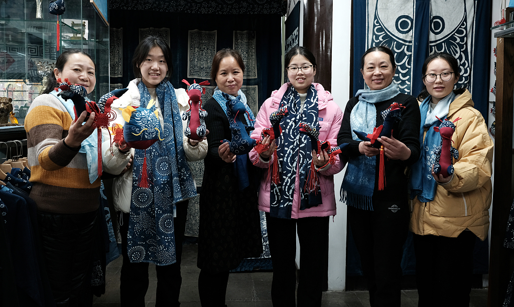 Photo taken on January 10, 2024 shows folk artists holding a blue calico 