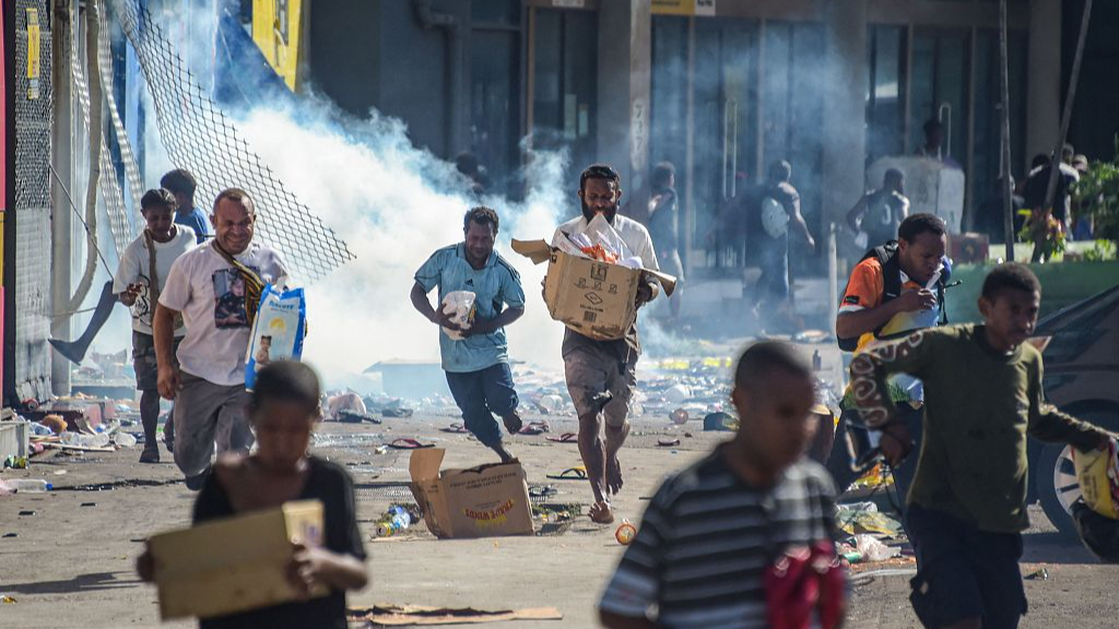 People run with merchandise as crowds leave shops with looted goods amid a state of unrest in Port Moresby, Papua New Guinea, January 10, 2024. /CFP