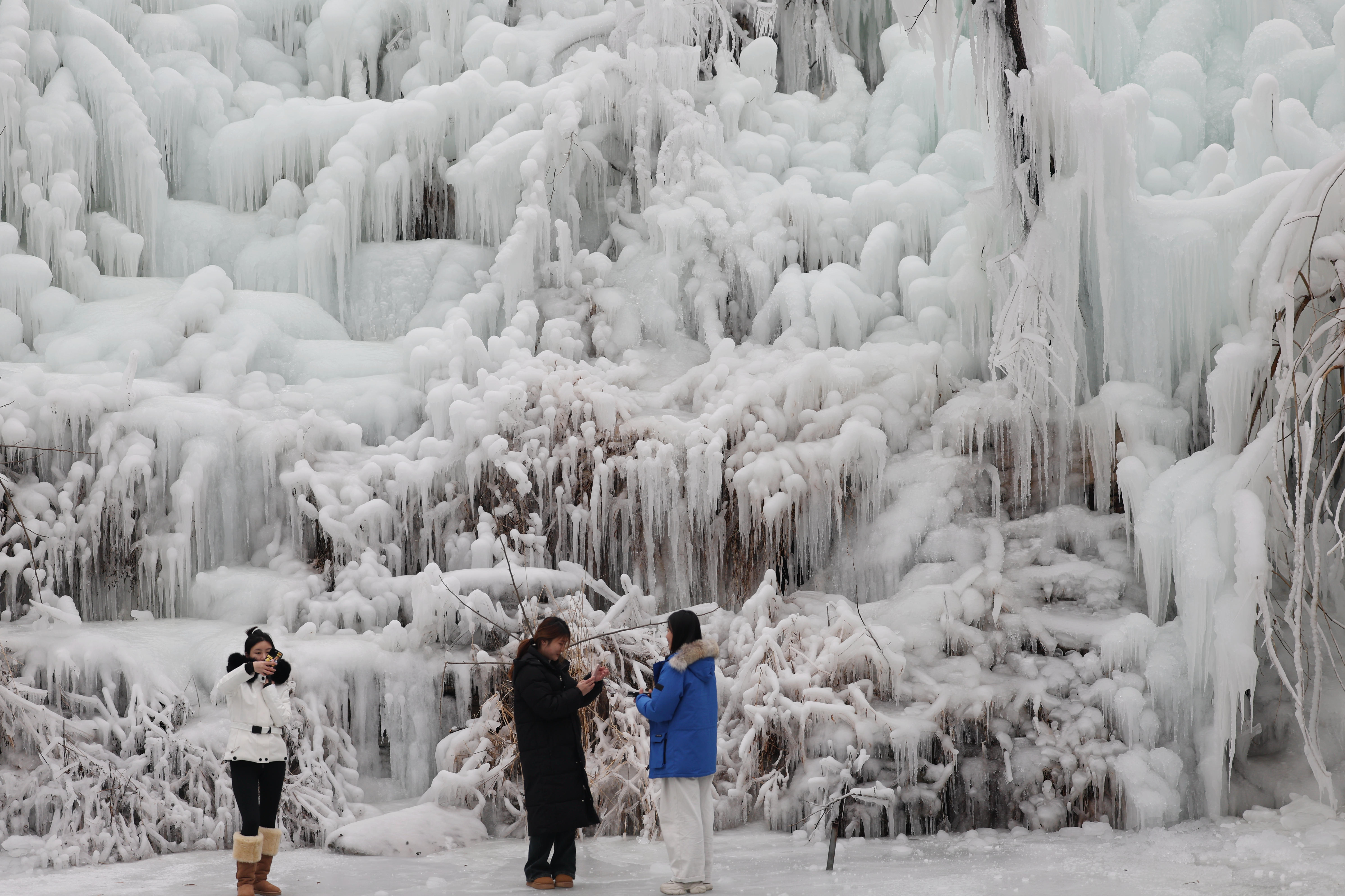 Visitors take photos of a frozen waterfall at the Xiangshan Mountain tourist spot in Linyi City, Shandong Province, January 9, 2024. /IC