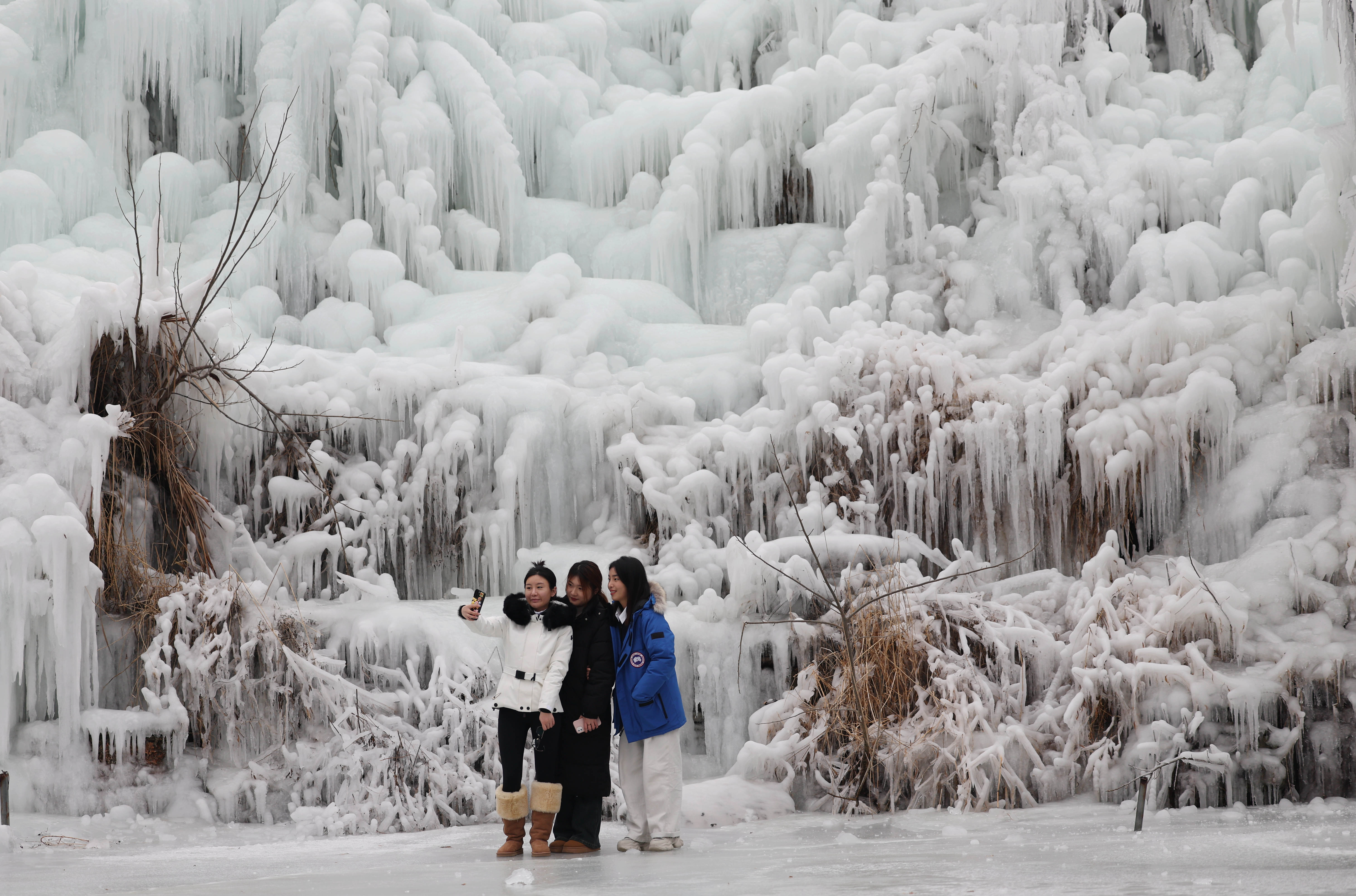 Visitors take photos of a frozen waterfall at the Xiangshan Mountain tourist spot in Linyi City, Shandong Province, January 9, 2024. /IC