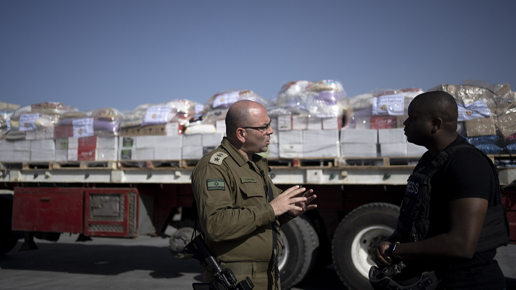 An Israeli soldier speaks to a journalist as trucks carrying humanitarian aid bound for the Gaza Strip wait in a holding area at Kerem Shalom Crossing, January 10, 2024. /CFP