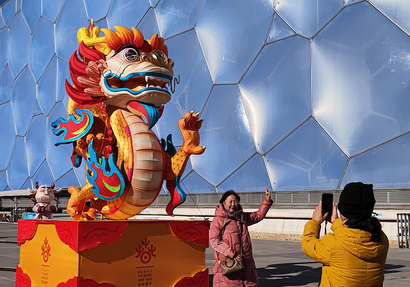 Residents take photos with a loong-themed art installation outside the National Aquatics Center in Beijing, January 14, 2024. /CFP