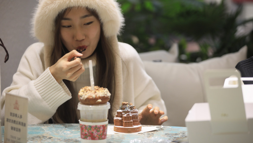 A customer enjoys eating a cake shaped like Harbin's Saint Sophia Cathedral in Harbin, northeast China's Heilongjiang Province, January 12, 2024. /CFP