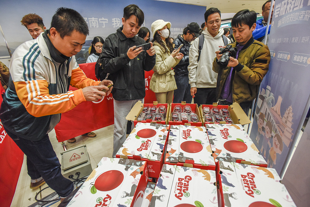 Residents take photos of cranberries sent from Heilongjiang's Fuyuan City in a mall of Nanning City, south China's Guangxi Zhuang Autonomous Region, January 11, 2024. /CFP