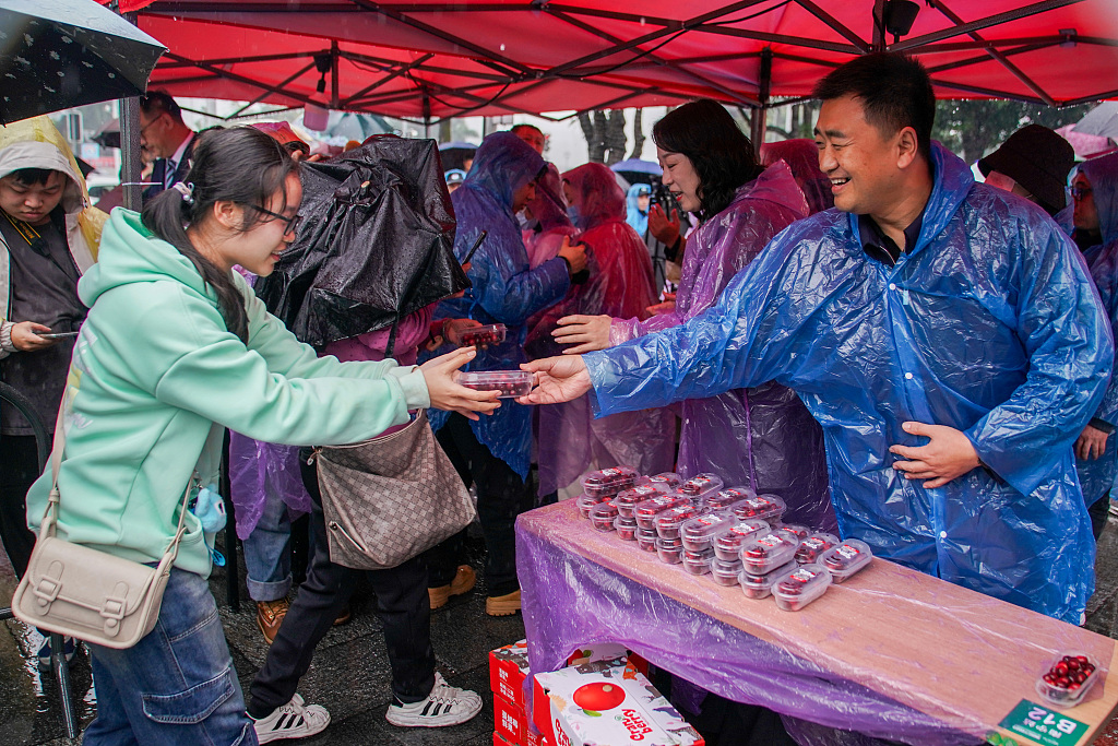 A resident receives a box of cranberries sent from Heilongjiang's Fuyuan City in a public square of Nanning City, south China's Guangxi Zhuang Autonomous Region, January 11, 2024. /CFP