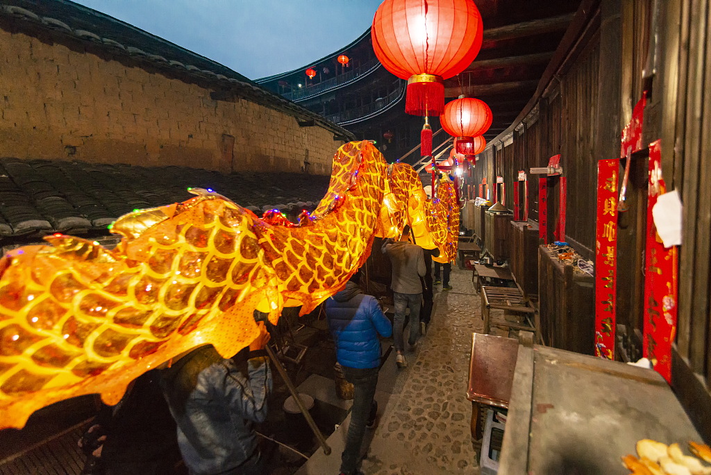 A file photo shows people carrying a loong (dragon) lantern at a Tulou building in Longyan, Fujian Province, China. /CFP