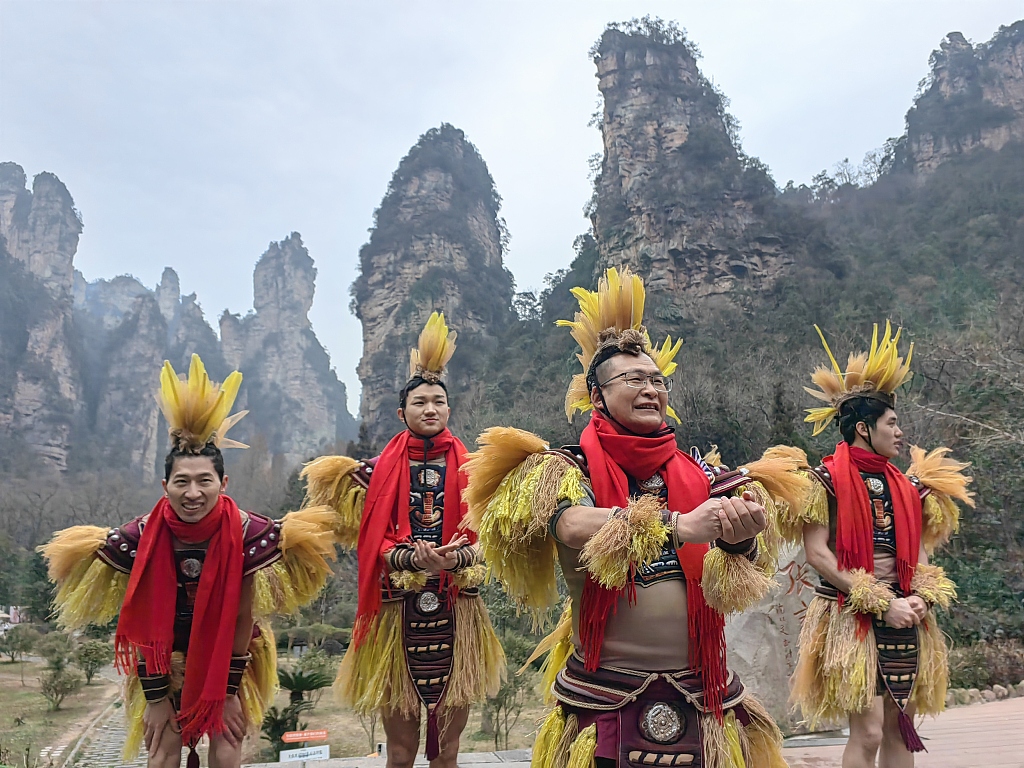 Peng Zhenhua (second from right), director of Wulingyuan District's Cultural and Tourism Bureau performs the Maogusi dance along with performers to welcome visitors to the Zhangjiajie National Forest Park on January 15, 2024, Zhangjiajie City, Hunan Province. /CFP