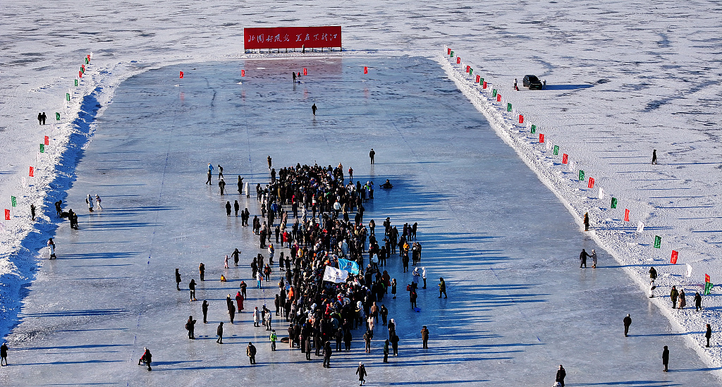 People watch a dragon boat tug-of-war on the frozen surface of the Songhua River in Harbin, Heilongjiang Province on January 14, 2024. /CFP