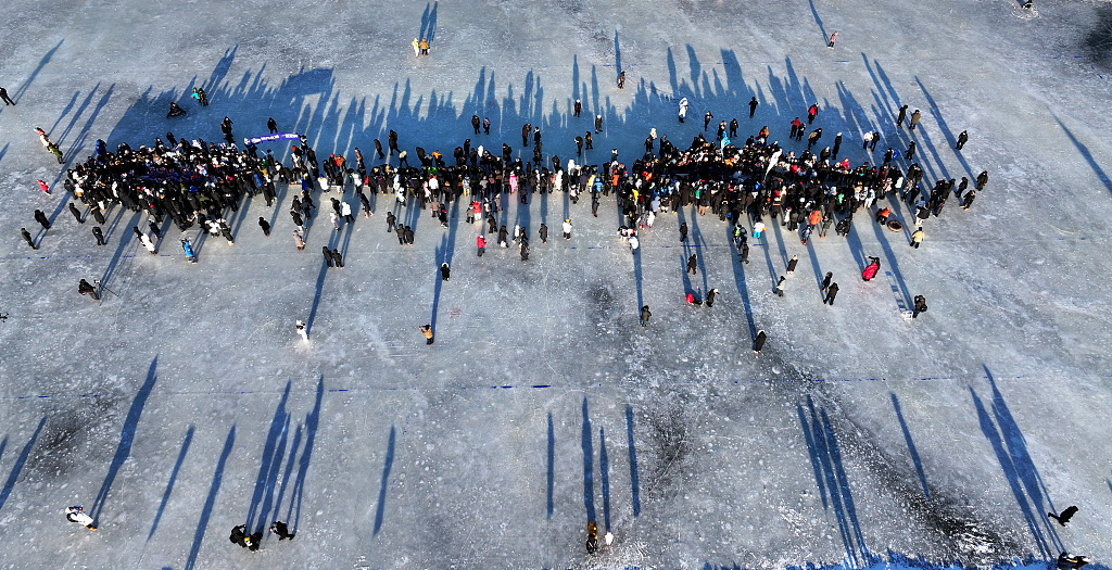 People watch a dragon boat tug-of-war on the frozen surface of the Songhua River in Harbin, Heilongjiang Province on January 14, 2024. /CFP