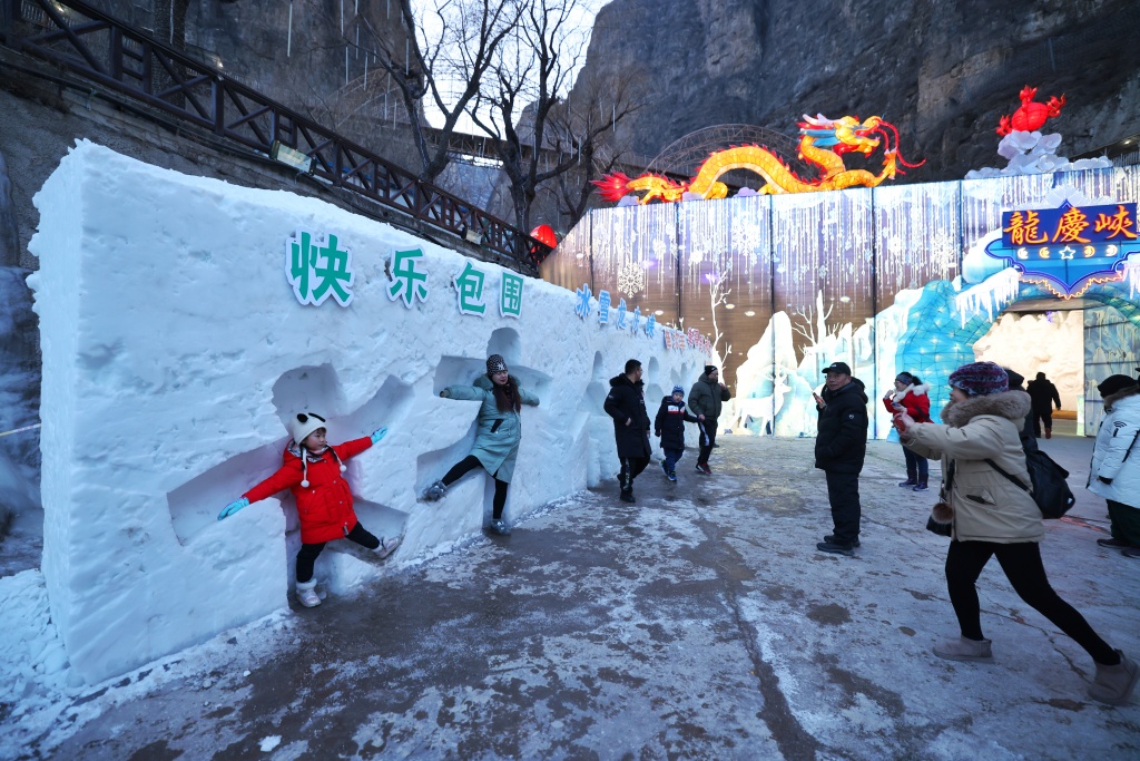 A photo shows people posing in a carved-out snow feature at the 38th Longqing Gorge Ice Lantern Festival in Yanqing District, Beijing on January 15, 2024. /CFP