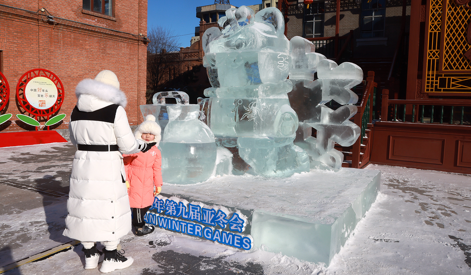 Visitors prepare to take photos with an ice sculpture of the Asian Winter Games mascot Nini presenting a jar of liquor at the Laodaowai baroque scenic spot in Harbin, Heilongjiang Province on January 14, 2024. /IC