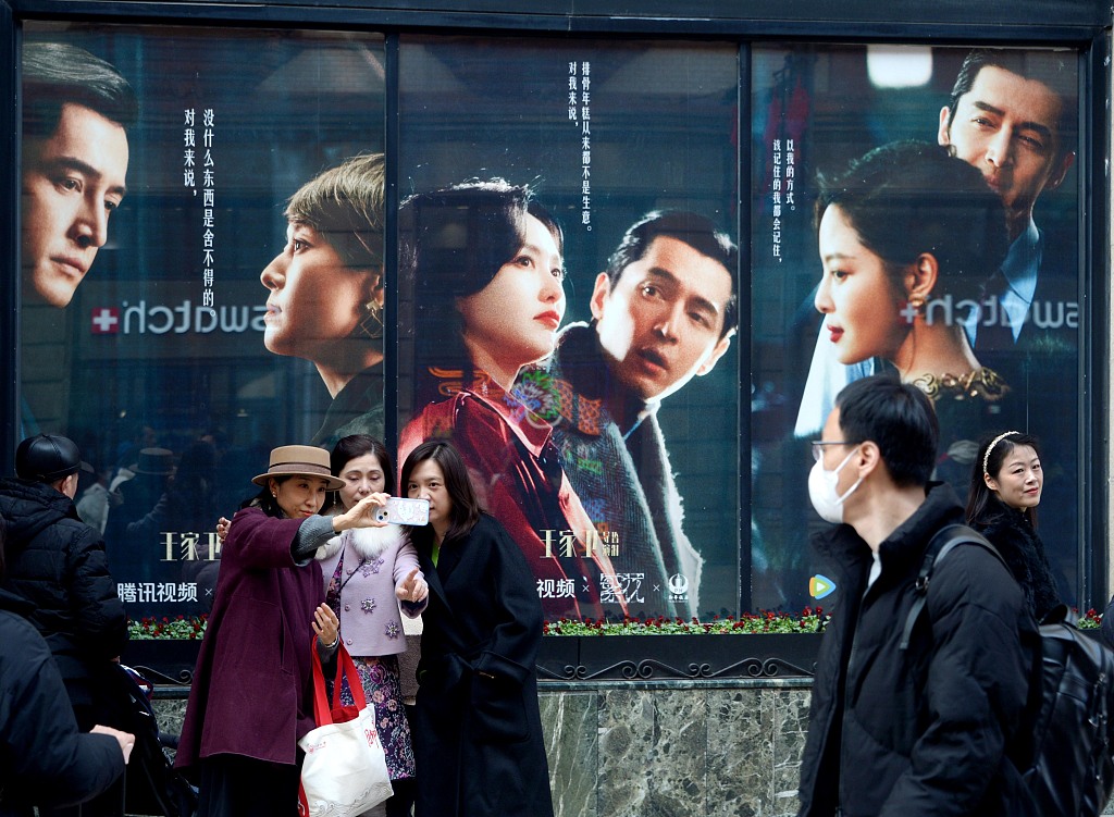 Visitors pose for photos in front of posters for the Chinese TV series 