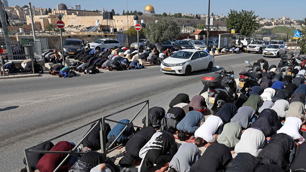 Palestinian Muslims perform the Friday noon prayer on a street blocked by Israeli security forces in the east Jerusalem neighbourhood of Ras al-Amud, on January 19, 2024 as age restrictions have been imposed to access the Al-Aqsa Mosque compound, amid the ongoing battles between Israel and the Palestinian group Hamas. /CFP