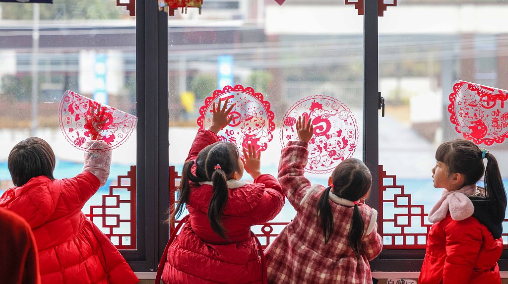 Children wearing red clothes put up window decorations at a kindergarten in Tongren, Guizhou Province to welcome the Spring Festival, January 18, 2024. /CFP