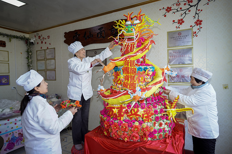 Workers help Xie Yunxian decorate a loong-shaped dough sculpture in preparation for the upcoming Chinese New Year in Yuncheng, Shanxi Province, January 23, 2024. /CFP