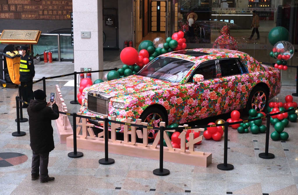 Photo shows a passerby taking a picture of a Rolls-Royce covered in a flower pattern at shopping mall in Shenyang, Liaoning Province on January 23, 2024. /IC