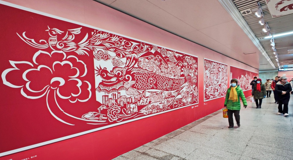 A photo shows metro passengers passing a paper-cutting art mural at a subway station in Wuhan, Hubei Province on January 22, 2024. /IC 