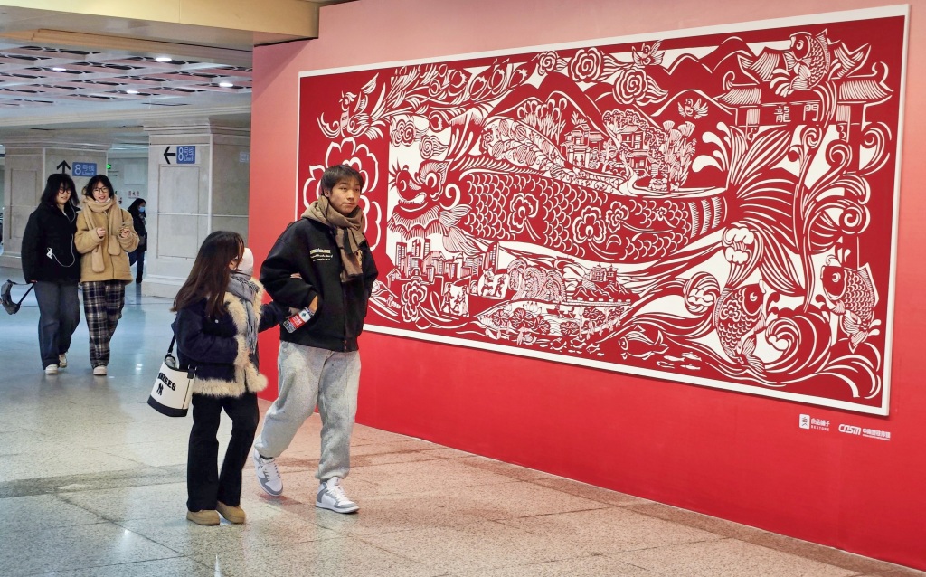 A photo shows metro passengers passing a paper-cutting art mural at a subway station in Wuhan, Hubei Province on January 22, 2024. /IC 