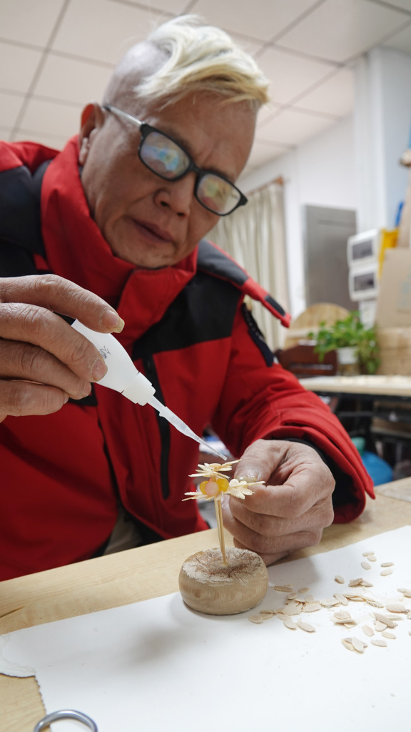 Photo taken on January 24, 2024 in Zhuhai, Guangdong, shows a craftsman working on a model of a flower made from upcycled disposable tableware. /CFP