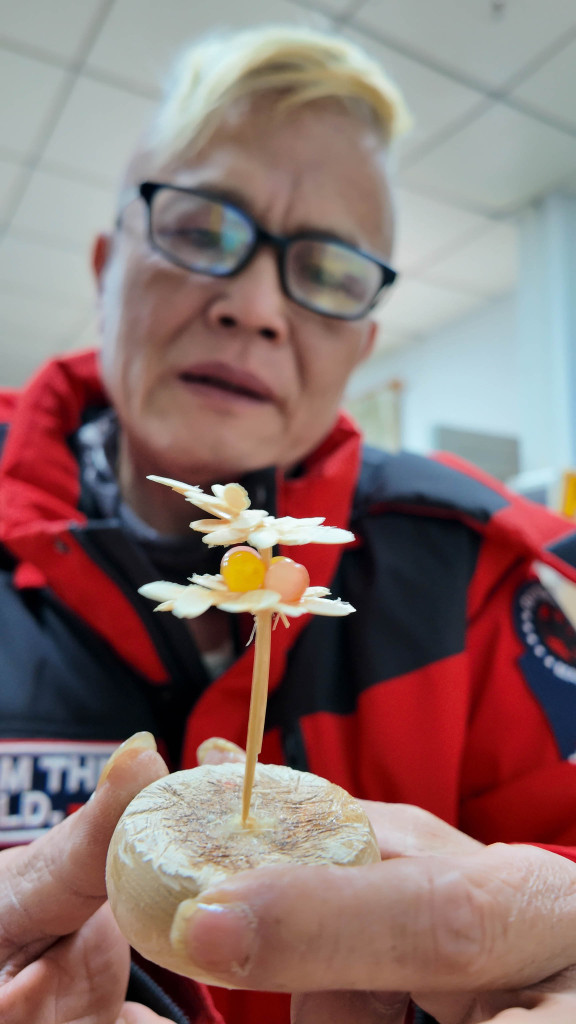 Photo taken on January 24, 2024 in Zhuhai, Guangdong, shows a craftsman holding a model of a flower made from upcycled disposable tableware. /CFP