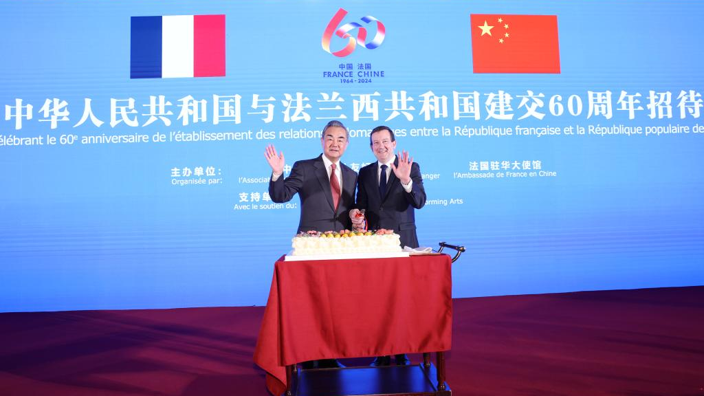 Chinese Foreign Minister Wang Yi, also a member of the Political Bureau of the Communist Party of China Central Committee, and Bertrand Lortholary, French Ambassador to China, wave hands after cutting a cake together at a reception for the 60th anniversary of the establishment of diplomatic ties between China and France in Beijing, capital of China, January 25, 2024. /Xinhua