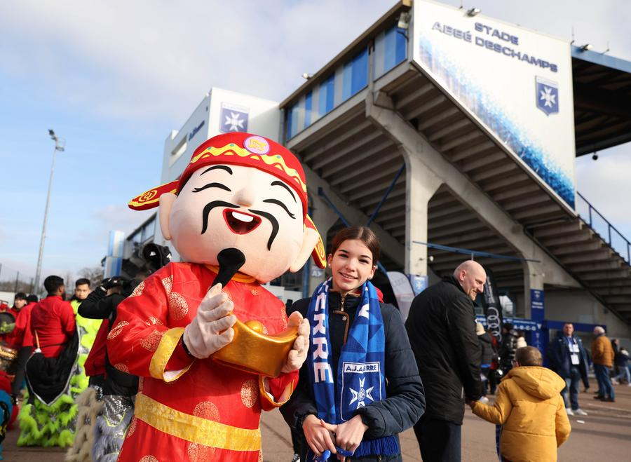 An Auxerre fan poses with a performer dressed up as the god of fortune outside the Abbe Deschamps Stadium of Auxerre club before a French Ligue 1 match between Auxerre and Montpellier as part of the 