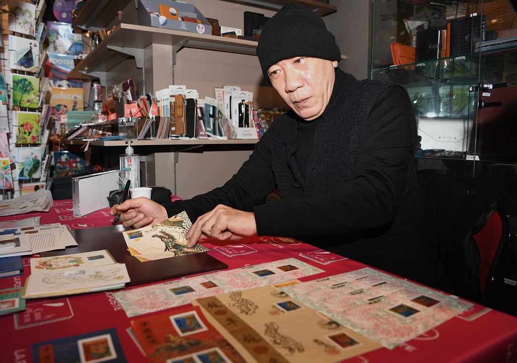 Chinese French artist Chen Jianghong, designer of France's Year of the Loong stamps, signs souvenirs for collectors in Paris, on January 26, 2024. /CFP