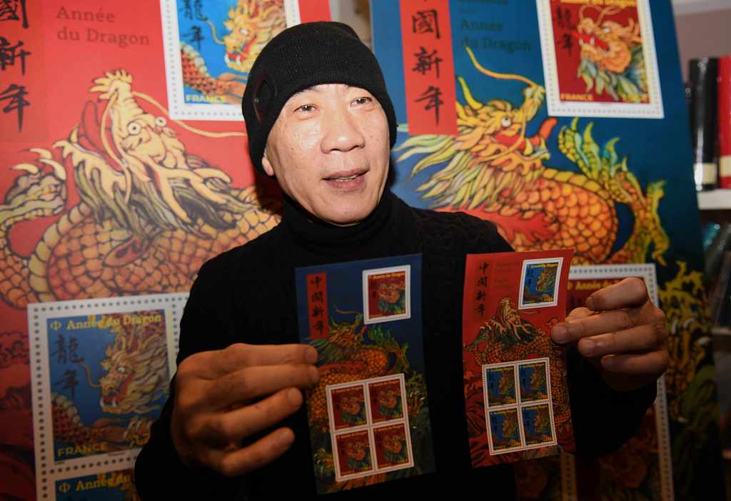 Chinese French artist Chen Jianghong, designer of France's Year of the Loong stamps, showcases souvenir sheets to cameras in Paris, on January 26, 2024. /CFP
