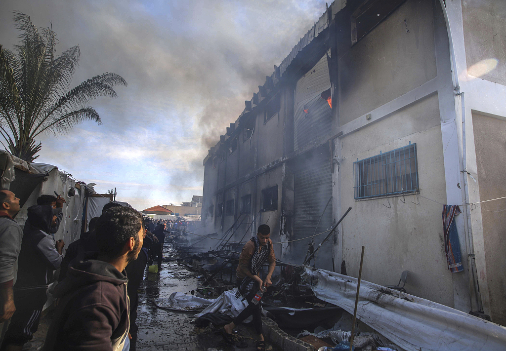 Palestinians try to extinguish a fire at a building of an UNRWA vocational training center which displaced people use as a shelter, after being targeted by Israeli tank shell in Khan Younis, January 24, 2024. /CFP